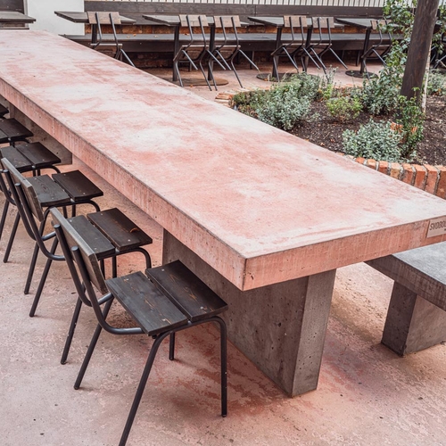 Podlouhlý betonový stůl s betonovou lavicí značky SVOBODA A SYN vyrobený na míru pro venkovní prostory restaurace